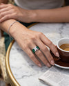AELIA Flex Ring in Aventine Green, worn at a café table